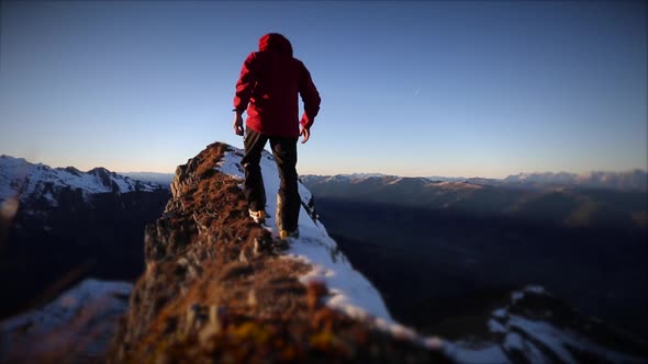 A man reaching the summit after climbing on a snow covered mountain.