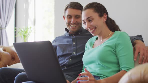 A young caucasian couple talking and paying their bills using a laptop