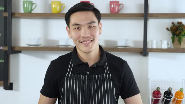 Portrait of Young asian male barista smiling, crossed arms, giving thumb up