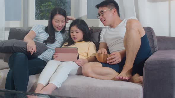 Young Asian family and daughter happy using tablet at home.