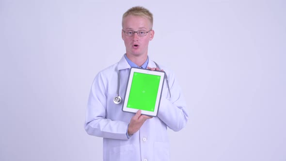 Young Blonde Man Doctor Talking While Showing Digital Tablet