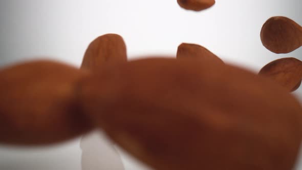 Almonds falling on surface. Slow Motion.