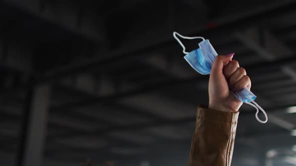 Part of african american woman hand protesting while holding face mask in empty parking garage