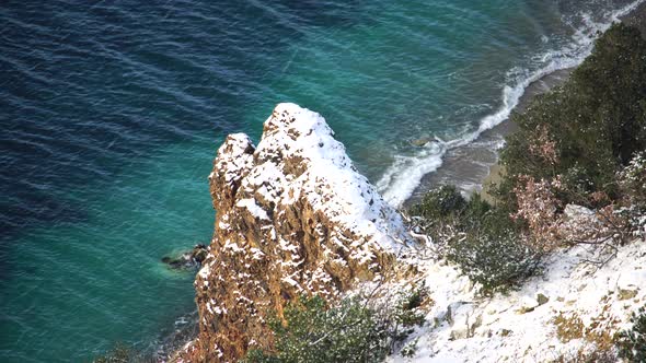 Snow Covered Rocky Cliffs Over Sea