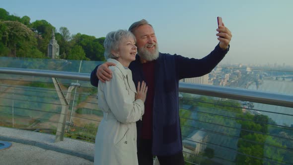 Grandparents Smiling and Taking Selfies While Standing on Terrace
