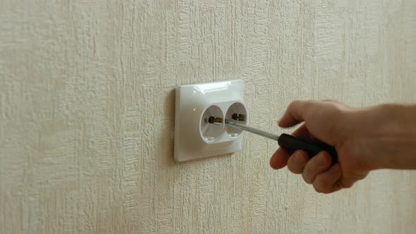 Close-up of a man repairing an electrical outlet in an apartment. An electrician fixes a loose outle