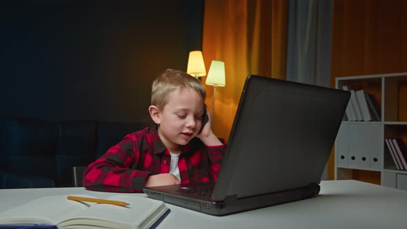 Attantive Teen Preschoolboy Doing Homework on Laptop During Phone Conversation at Home