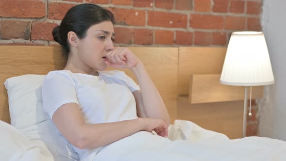 Young Indian Woman Coughing while Sitting in Bed