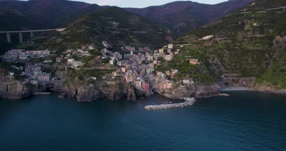 Colorful houses of coastal village hugs mountainside, Riomaggiore; drone