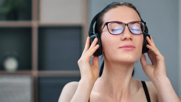 Closeup Face of Adorable Young Brunette Woman in Eyeglasses Relaxing on Couch Listening Music