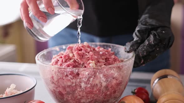 Adding Water to Minced Meat with Onion and Spices in a Glass Bowl Making Cutlets