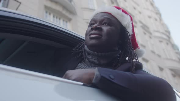 African American Businessman with Santa Hat Looking Through the Window of His Car