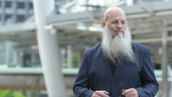 Mature Bearded Bald Businessman Wearing Sunglasses in the City Outdoors