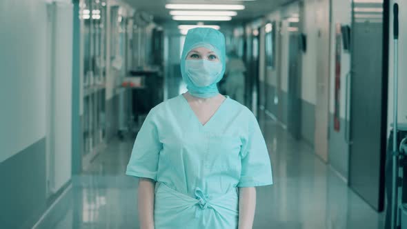 Female Surgeon in Medical Uniform is Looking Into the Camera