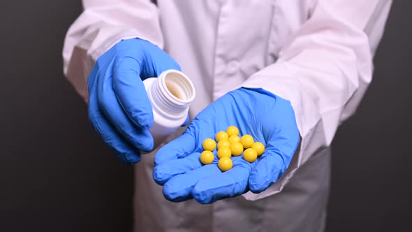 A Man in a White Medical Robe and Blue Gloves Put the Yellow Pills for a Patient