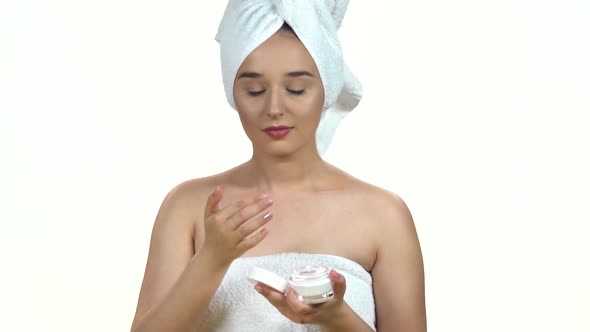 Portrait of Young Woman in White Towel on Her Head Applying a Cream on Her Previously Cleansed Face