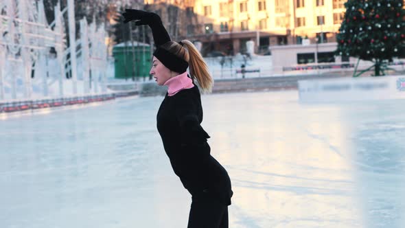 Young Woman Training Her Figure Skating on Public Ice Rink Outdoors