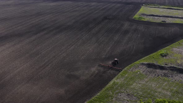 Aerial shot of tractor cultivating large unplanted field.  Agricultural machines working in farmland