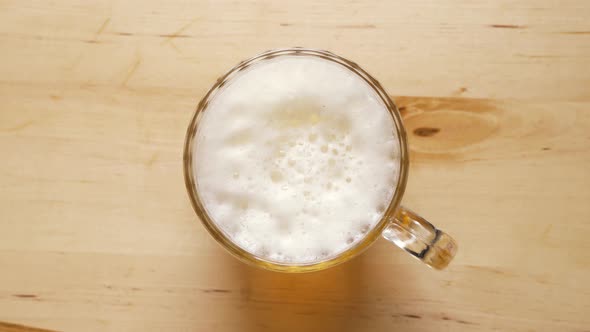 Top View of Pint of Light Beer with Foam on Wooden Table