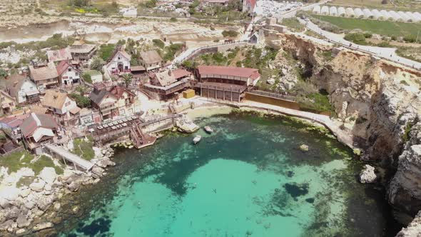 Mediterranean shore of Anchor Bay on Popeye Village in Malta - Aerial orbit shot