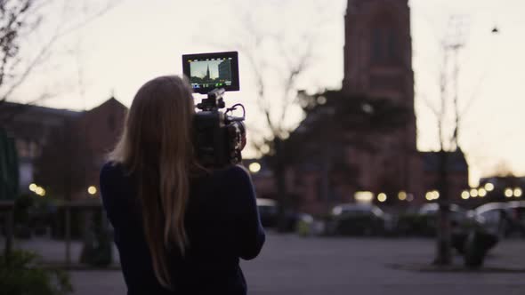 Female Film Maker Filming Church Tower In City