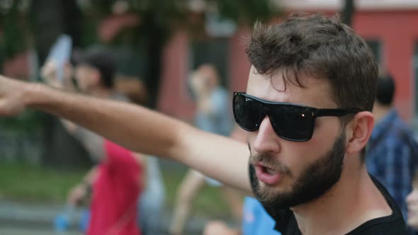 Rioting Rebel Activist with Beard in Eyeglasses Marching and Waves Arm with Fist