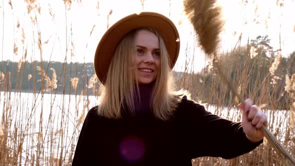 Millennial Woman Caucasian Blonde Woman Waving Pampas Grass with Beige Hat in Black Sweater in the