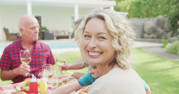 Portrait of happy caucasian woman having breakfast with family in garden