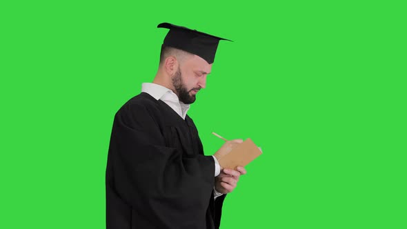 Thoughtful Graduation Man Writing Down His Goals on a Green Screen, Chroma Key.