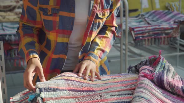 African American Woman with an Afro Hairstyle Carefully Chooses a Carpet in a Furniture Store Close