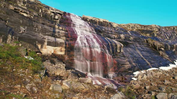 Aerial View Of Waterfall Cascading Down Red Coloured Rock Face At Hardangervidda National Park. Low