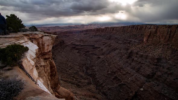 Time lapse over looking desert canyon as man walks to ledge