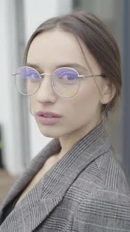 Vertical Video. Beautiful Girl in Glasses and a Gray Suit. Slow Motion