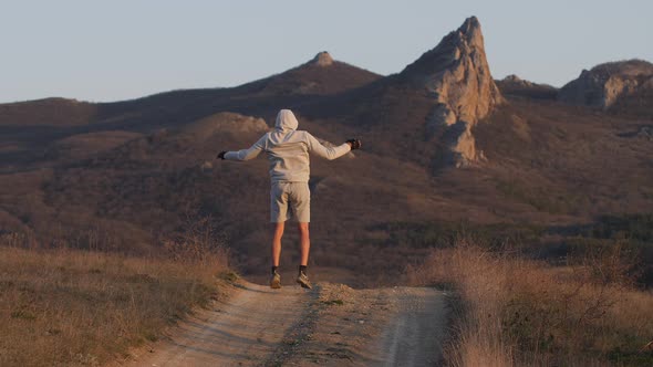 Man Performs Exercise on Country Road Amid Mountains in Sunset