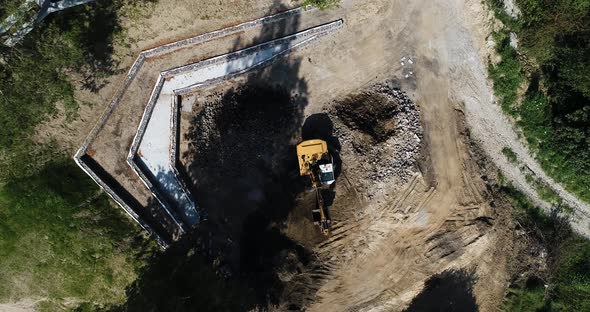 Yellow crave aerial top down view of excavator truck working in remote area construction site for bu