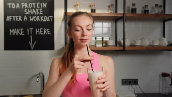 Athlete woman drinking a protein shake from a straw