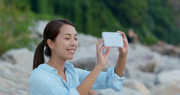 Woman take photo on cellphone at seaside