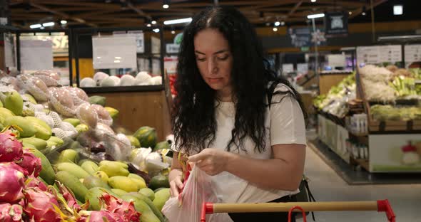 Woman Makes Purchases in the Supermarket Healthy Food Dragon Fruit Puts in a Basket to Be Weighed