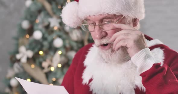 Close-up of Surprised Santa Claus Reading Letter, Looking at Camera and Shaking His Head. Old