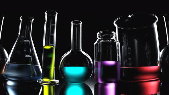 Laboratory glassware with colorful liquids inside on a black background looping.