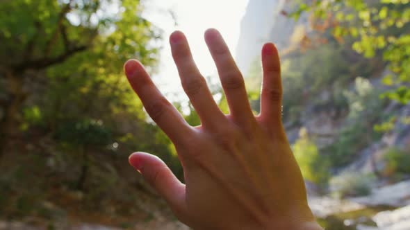 Girl Enjoys Rays of Sun That Shine Between Her Fingers