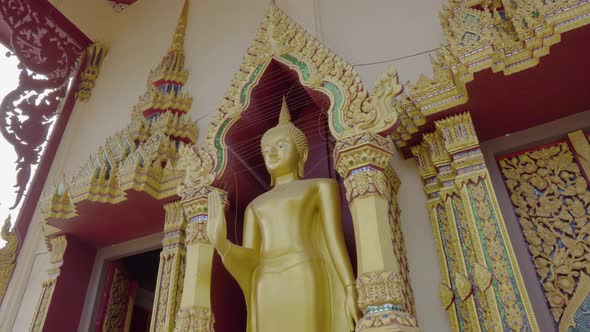 Golden Buddha standing statue at the Plai Laem temple in Koh Samui panning shot low angle view