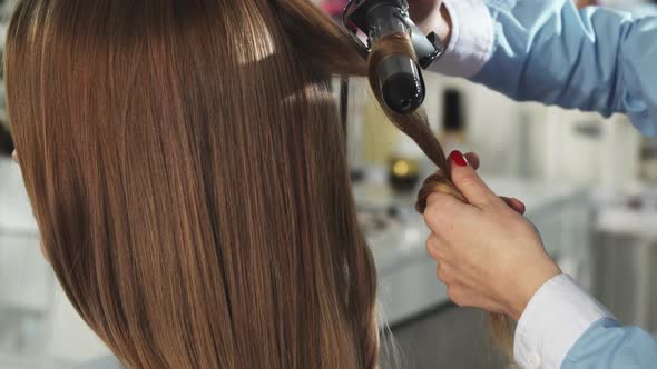 Rearview Close Up of a Woman Getting Her Hair Curled By a Professional Hairstylist