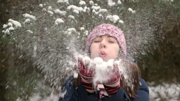 Young Woman Blowing Snowflakes to the Camera