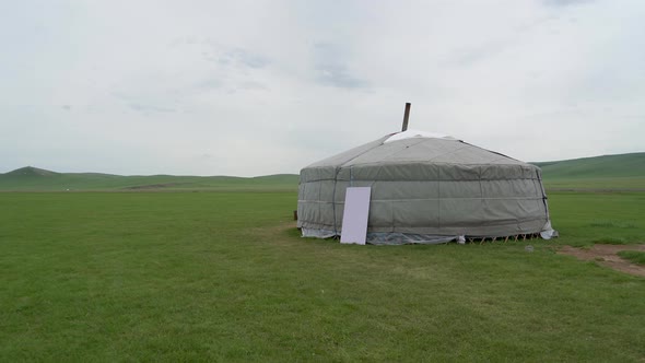 A Gray Mongolian Ger Tent Alone in Vast Green Meadow