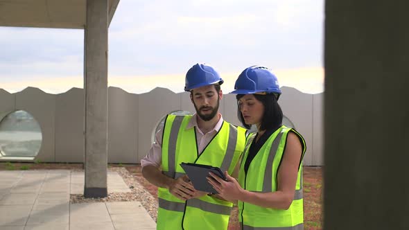 Man and woman discussing with digital tablet at construction site