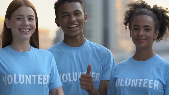 Extremely Happy Multiracial Volunteer Friends Showing Thumbs-Up Camera, Charity