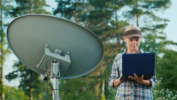 Technician Sets Up a Terrestrial Satellite Dish, Uses a Laptop