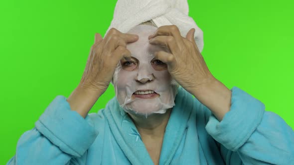 Elderly Grandmother After Shower. Old Woman Applying Cosmetic Fabric Face Mask