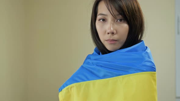 Portrait of an Asian Woman with a Ukrainian Flag on Her Shoulders